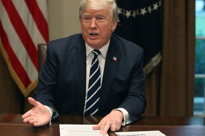 Trump at a table pointing to papers.